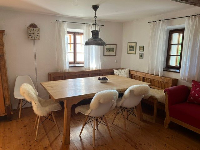 Esszimmer mit großem Holztisch, Schaffell-Stühlen und Industrieleuchte