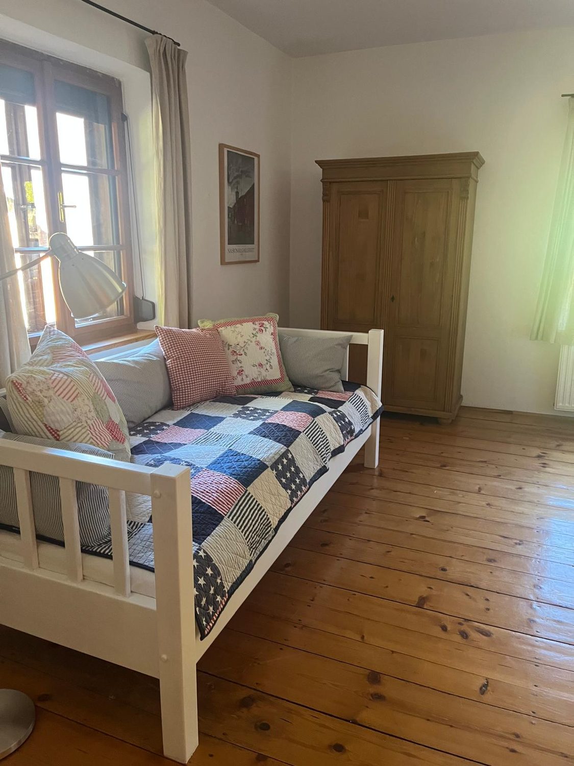 Zimmer mit weißem Tagesbett, Patchwork-Decke und Pinienschrank