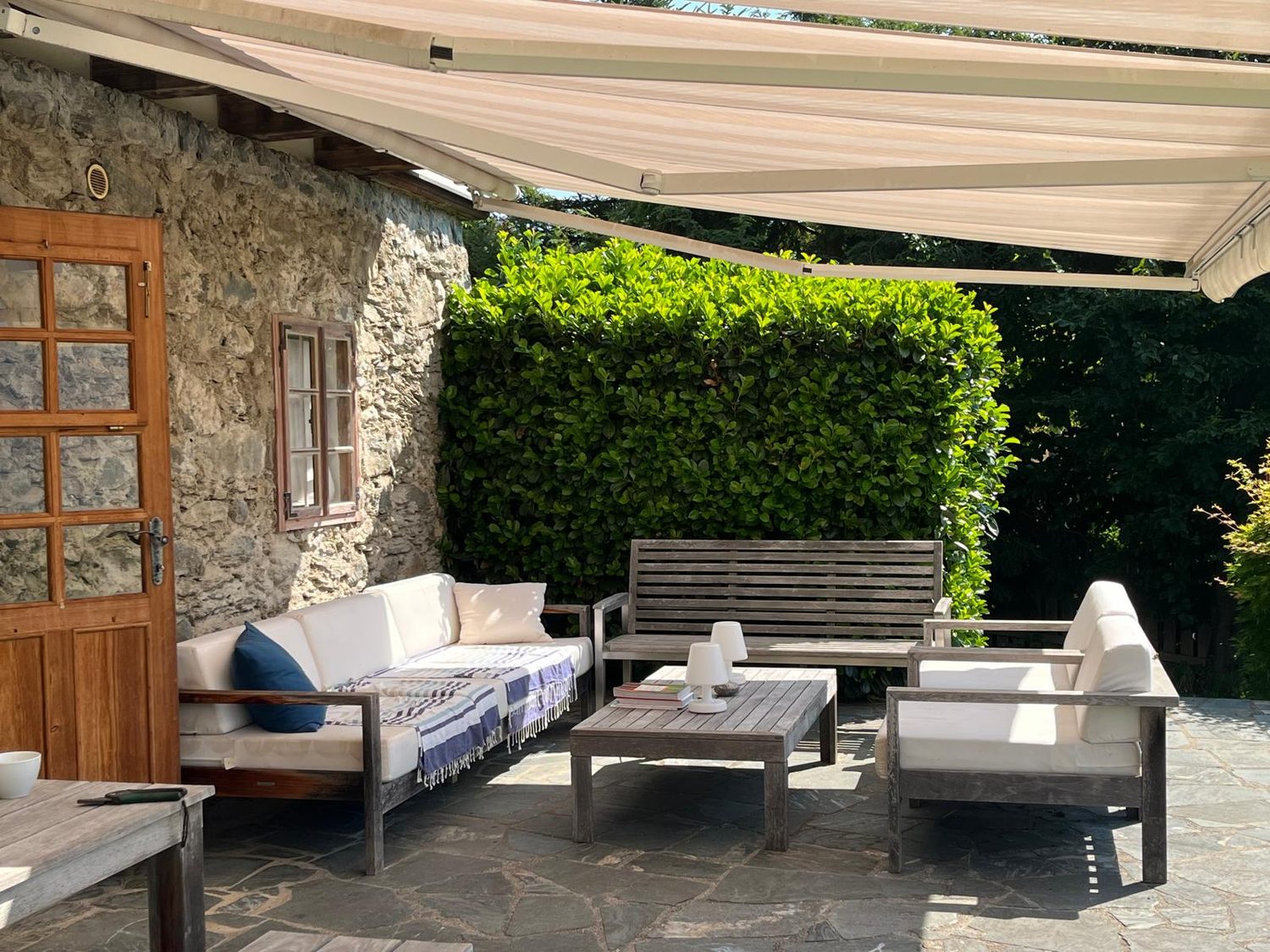 Terrasse mit Markise, Loungemöbeln und Natursteinmauer