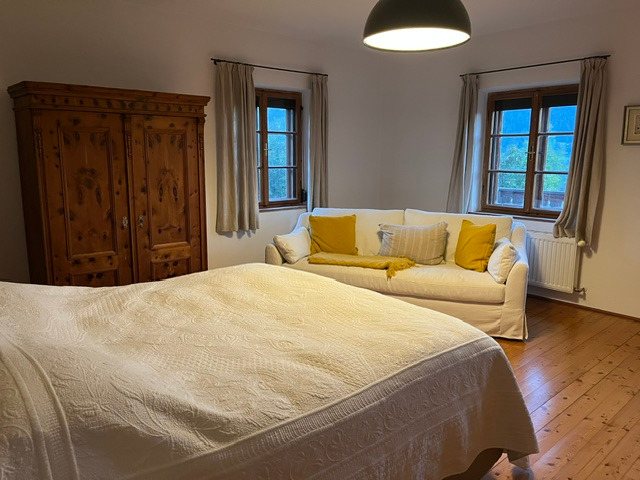 Helles Schlafzimmer mit Doppelbett, Sofa und Pinienschrank